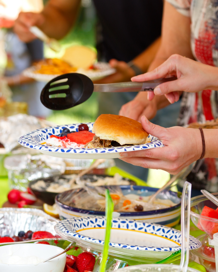 Goście nakładający jedzenie na talerze w trakcie imprezy integracyjnego